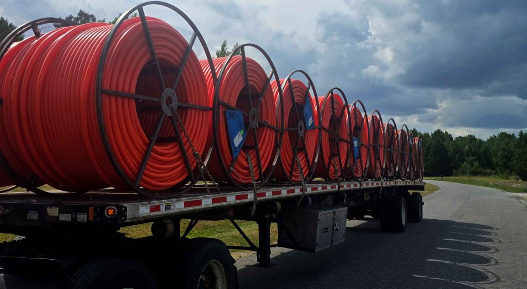 Flatbed service transporting large conduit spools by TA Trans Inc.