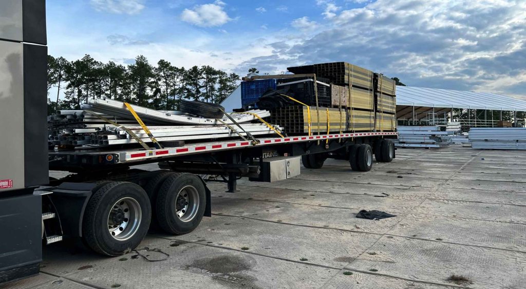 TA Trans Inc Flatbed service trailer loaded with staging construction materials at a job site.