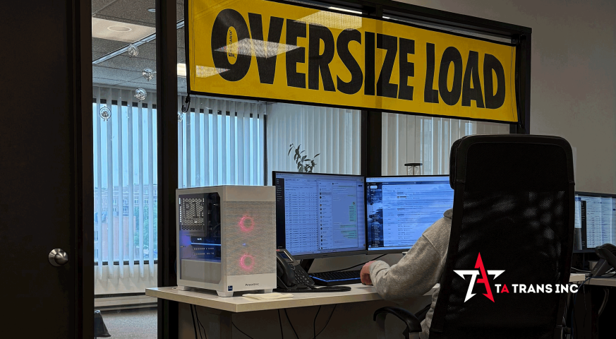 TA Trans dispatch office with oversized load banner and real-time freight tracking monitors