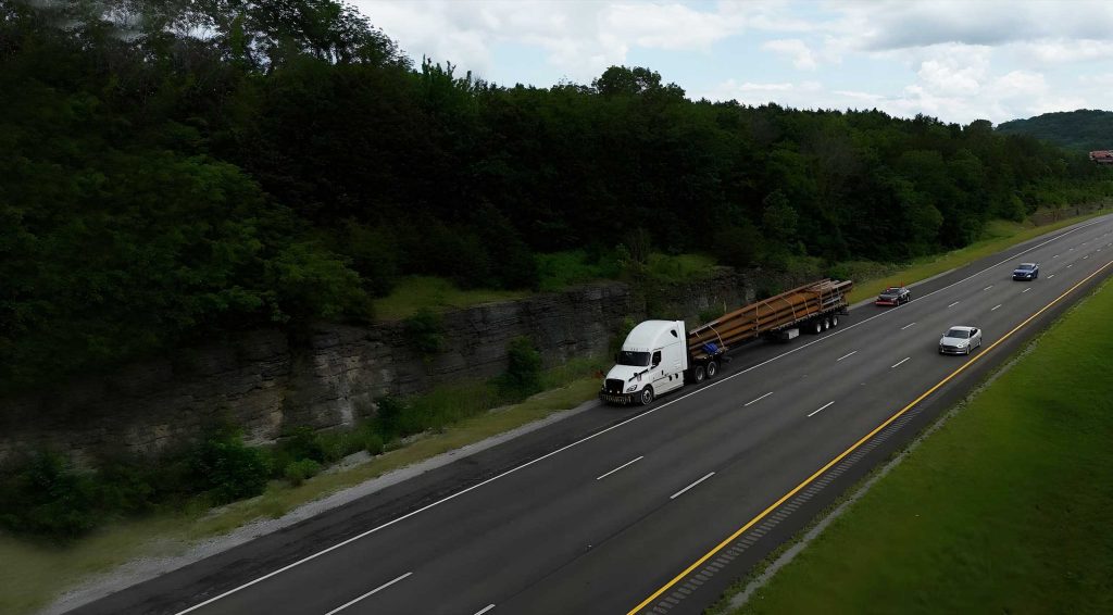 TA Trans truck hauling a stretch-flatbed load on the highway