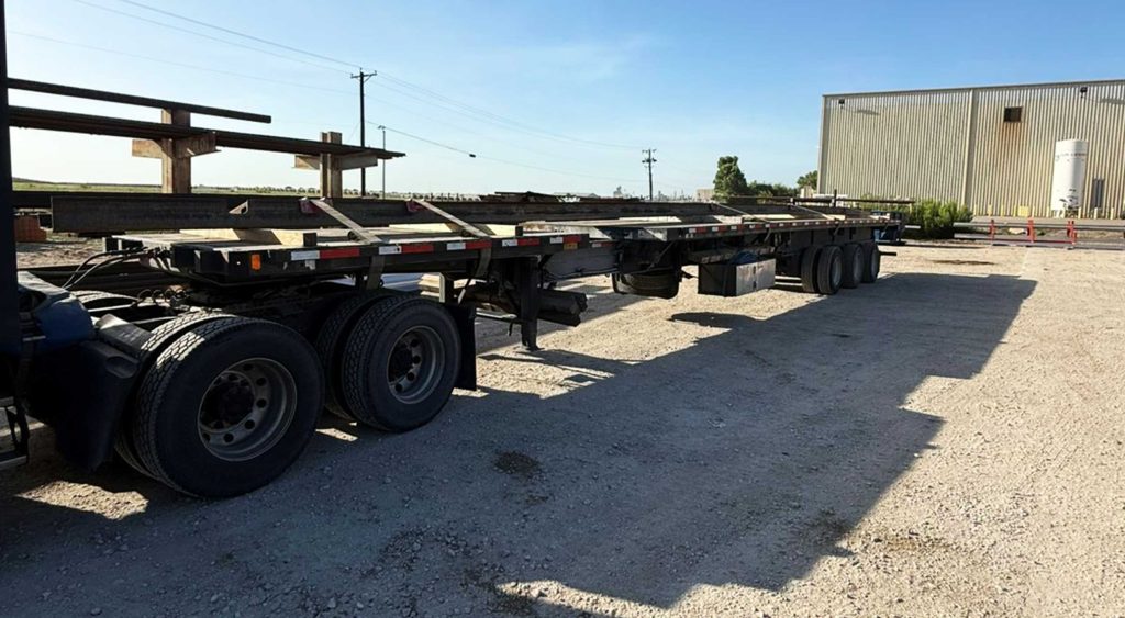 Stretch flatbed trailer ready to haul an overdimension railcar side sill assembly.