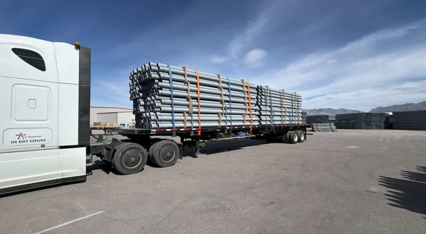 flatbed trailer hauling steel pipes secured with straps industrial freight flatbed trucking demand