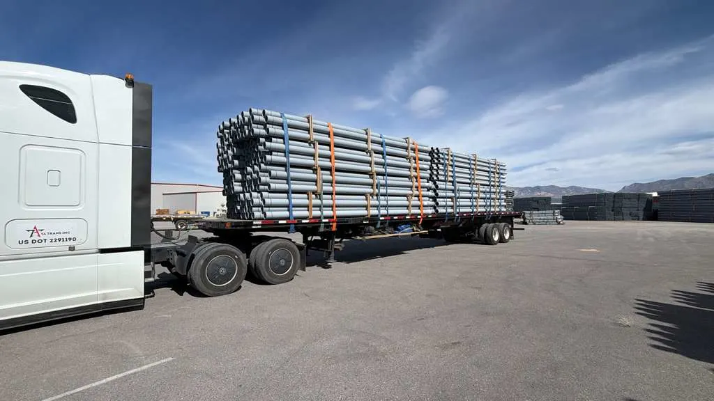 flatbed trailer hauling steel pipes secured with straps industrial freight flatbed trucking demand