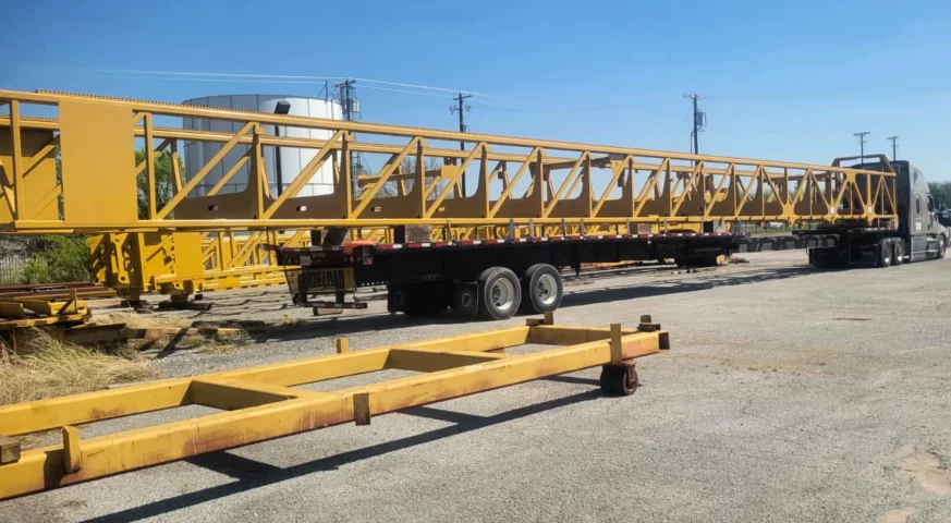Stretch flatbed hauling 114 ft mast secured for transport