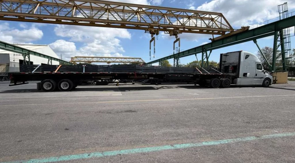 Flatbed trailer hauling secured steel joists with straps