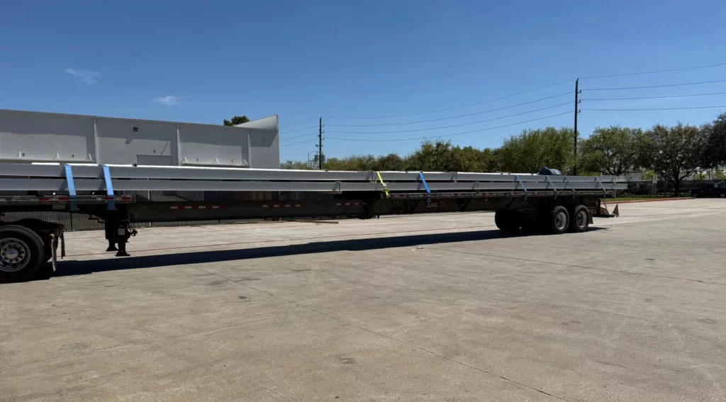 Stretch flatbed hauling long fiberglass panels secured with straps