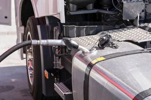Fuel nozzle inserted into the diesel tank of a commercial semi-truck.