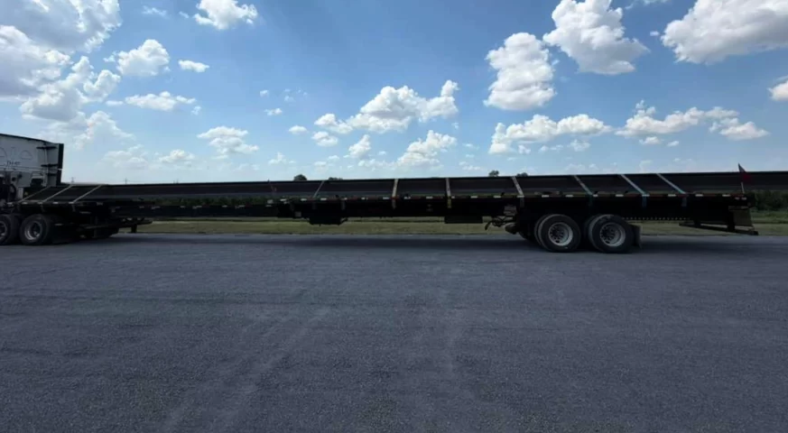 82-foot steel beams secured with straps on an extended stretch trailer for specialized transportation.